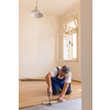DIY, repair, building and home concept - senior man lying parquet floor board/laminate flooring (shallow DOF; color toned image)