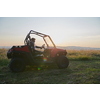 portrait of young happy excited man enjoying beautiful sunny day while driving a off road buggy car on mountain nature