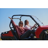 portrait of young two happy girls enjoying a beautiful sunny day while driving an off-road car in a carriage in mountain nature