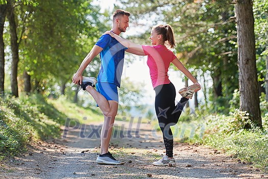 young happy couple enjoying in a healthy lifestyle warming up and stretching before jogging on a country road through the beautiful sunny forest, exercise and fitness concept young happy couple enjoying in a healthy lifestyle warming up and stretching before jogging on a country road through the beautiful sunny forest, exercise and fitness concept