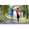 young happy couple enjoying in a healthy lifestyle warming up and stretching before jogging on a country road through the beautiful sunny forest, exercise and fitness concept