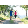 young happy couple enjoying in a healthy lifestyle while jogging on a country road through the beautiful sunny forest, exercise and fitness concept