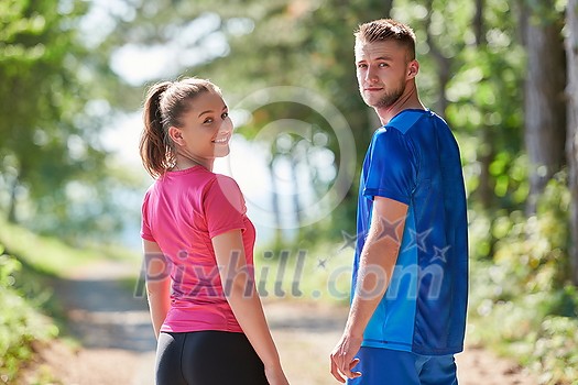 young happy couple enjoying in a healthy lifestyle while jogging on a country road through the beautiful sunny forest, exercise and fitness concept young happy couple enjoying in a healthy lifestyle while jogging on a country road through the beautiful sunny forest, exercise and fitness concept