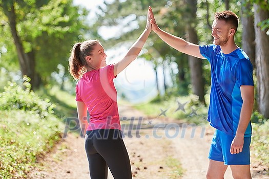 young happy couple enjoying in a healthy lifestyle while jogging on a country road through the beautiful sunny forest, exercise and fitness concept young happy couple enjoying in a healthy lifestyle while jogging on a country road through the beautiful sunny forest, exercise and fitness concept
