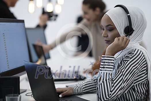 beautiful modern african Muslim businesswoman in office, wearing hijab speaking on headset at modern startup coworking space beautiful modern african Muslim businesswoman in office, wearing hijab speaking on headset at modern startup coworking space