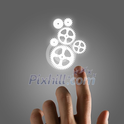 Close up of hand and gears mechanism on gray background Close up of hand and gears mechanism on gray background