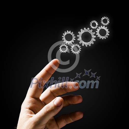 Close up of hand and gears mechanism on black background Close up of hand and gears mechanism on black background
