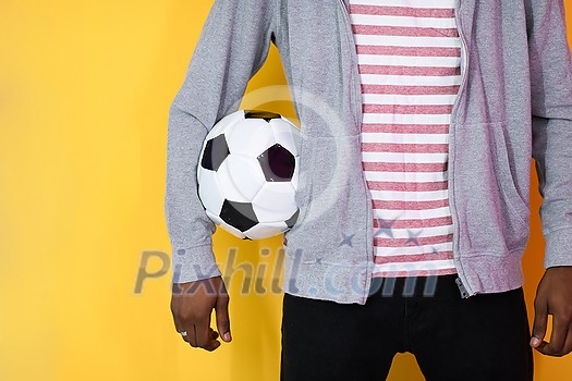 an afro man posing on a yellow background while holding a soccer ball in his hand
an afro man posing on a yellow background while holding a soccer ball in his hand