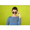 a beautiful woman  in sunglasses posing in front of a green background
