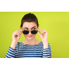 a beautiful woman  in sunglasses posing in front of a green background
