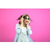 Gorgeous brunette lady in black glasses dancing and   listening music in headphones and singing on pink background.