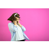 Gorgeous brunette lady in black glasses dancing and   listening music in headphones and singing on pink background.