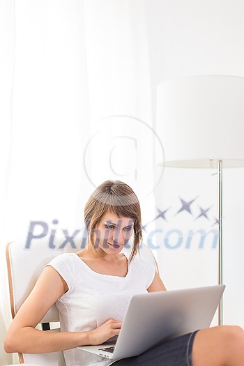 Young woman with laptop in her comfortable apartment Young woman with laptop in her comfortable apartment
