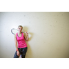 Cute young woman with a racket leaning against a wall in a squash court, ready for the game