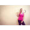 Cute young woman with a racket leaning against a wall in a squash court, ready for the game