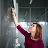 Pretty, young college student writing on the chalkboard, blackboard during a math class