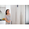 Pretty, young woman in her modern kitchen, by the fridge, about to cook a healthy meel for her family (color toned image)