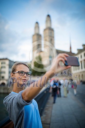 Pretty, female tourist taking selfies in front of the Grossmunster Church in Zurich, Switzerland Pretty, female tourist taking selfies in front of the Grossmunster Church in Zurich, Switzerland