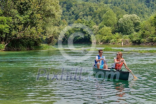 Couple adventurous explorer friends are canoeing in a wild river surrounded by the beautiful nature Couple adventurous explorer friends are canoeing in a wild river surrounded by the beautiful nature