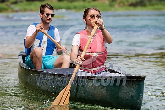 Couple adventurous explorer friends are canoeing in a wild river surrounded by the beautiful nature Couple adventurous explorer friends are canoeing in a wild river surrounded by the beautiful nature