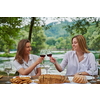 two young happy girlfriends having picnic french dinner party outdoor during summer holiday vacation near the river at beautiful nature