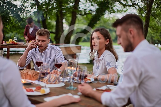 group of happy friends having picnic french dinner party outdoor during summer holiday vacation near the river at beautiful nature