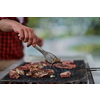 Man cooking tasty food on barbecue grill for outdoor french dinner party near the river on beautiful summer evening in nature