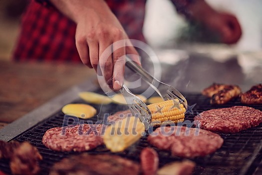 Man cooking tasty food on barbecue grill for outdoor french dinner party near the river on beautiful summer evening in nature Man cooking tasty food on barbecue grill for outdoor french dinner party near the river on beautiful summer evening in nature