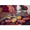 Man cooking tasty food on barbecue grill for outdoor french dinner party near the river on beautiful summer evening in nature