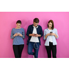 a group of friends have fun and dance while using a cell phone and headphones isolated on a pink background