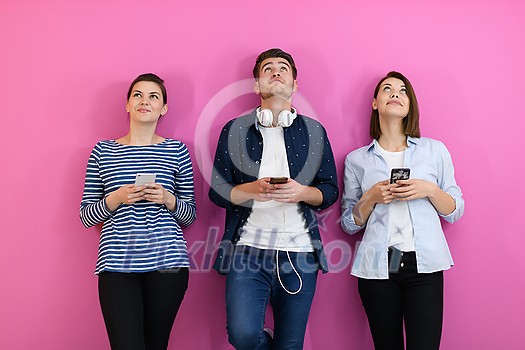 a group of friends have fun and dance while using a cell phone and headphones isolated on a pink background a group of friends have fun and dance while using a cell phone and headphones isolated on a pink background