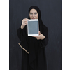 Young Arab businesswoman in traditional clothes or abaya and glasses showing tablet computer display in front of black chalkboard representing modern islam fashion and technology