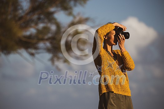 Pretty, young woman with a mirrorless camera, taking photos by the sea Pretty, young woman with a mirrorless camera, taking photos by the sea