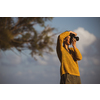 Pretty, young woman with a mirrorless camera, taking photos by the sea