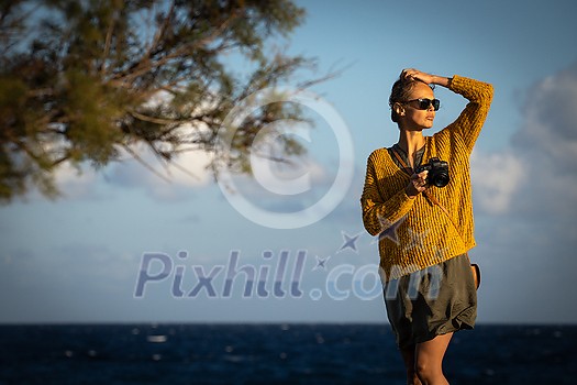 Pretty, young woman with a mirrorless camera, taking photos by the sea Pretty, young woman with a mirrorless camera, taking photos by the sea