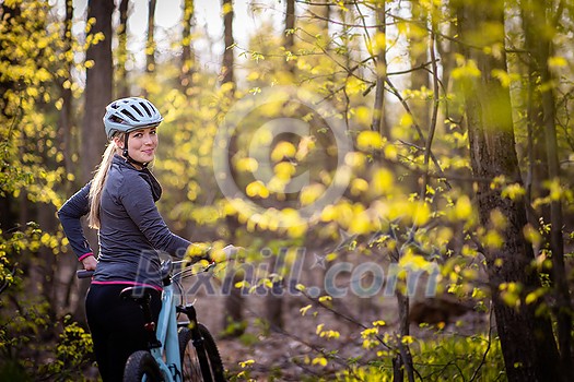 Pretty, young woman with her mountain bike going for a ride past the city limits, getting her dose of daily cardio Pretty, young woman with her mountain bike going for a ride past the city limits, getting her dose of daily cardio