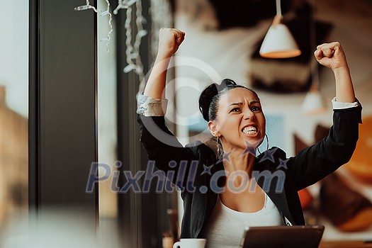 a woman sits in a cafe with her arms raised and celebrating a job well done