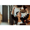 a woman sits in a cafe with her arms raised and celebrating a job well done