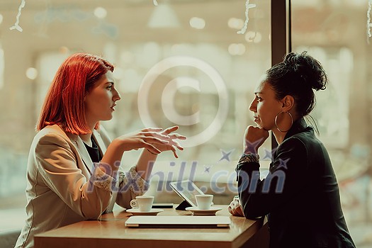 One-on-one meeting.Two young business women sitting at table in cafe.Girl using laptop, smartphone, blogging. Teamwork, business meeting. Freelancers working. One-on-one meeting.Two young business women sitting at table in cafe.Girl using laptop, smartphone, blogging. Teamwork, business meeting. Freelancers working.