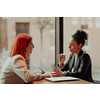 One-on-one meeting.Two young business women sitting at table in cafe.Girl using laptop, smartphone, blogging. Teamwork, business meeting. Freelancers working.