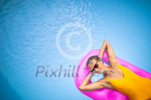 Young Beautiful Suntanned Woman wearing sunglasses relaxing next to a Swimming Pool on a lovely Summer Day Young Beautiful Suntanned Woman wearing sunglasses relaxing next to a Swimming Pool on a lovely Summer Day