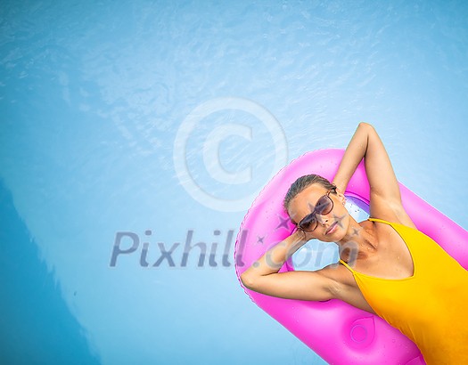 Young Beautiful Suntanned Woman wearing sunglasses relaxing next to a Swimming Pool on a lovely Summer Day Young Beautiful Suntanned Woman wearing sunglasses relaxing next to a Swimming Pool on a lovely Summer Day