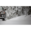 Car on a snowy winter road amid forests - using its four wheel drive capacities to get through the snow