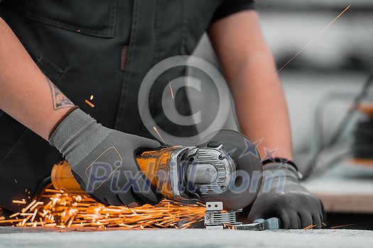 Heavy Industry Engineering Factory Interior with Industrial Worker Using Angle Grinder and Cutting a Metal Tube. Contractor in Safety Uniform and Hard Hat Manufacturing Metal Structures. High quality photo Heavy Industry Engineering Factory Interior with Industrial Worker Using Angle Grinder and Cutting a Metal Tube. Contractor in Safety Uniform and Hard Hat Manufacturing Metal Structures. High quality photo