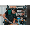 Heavy Industry Engineering Factory Interior with Industrial Worker Using Angle Grinder and Cutting a Metal Tube. Contractor in Safety Uniform and Hard Hat Manufacturing Metal Structures. High quality photo