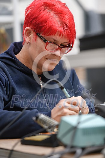 Industrial worker woman soldering cables of manufacturing equipment in a factory. High quality photo Industrial worker woman soldering cables of manufacturing equipment in a factory. High quality photo