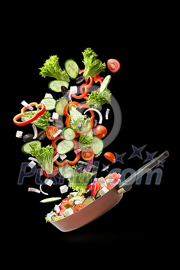 Frying pan with falling tasty fresh salad, cucumbers, tomatoes, olives, peppers and onions on white background