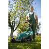 Senior gardenr gardening in his permaculture garden - mowing the lawn with an electrical lawn mower