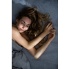 Pretty, young woman sleeping in her bed late in the morning on a weekend - compensating for the lack of sleep
