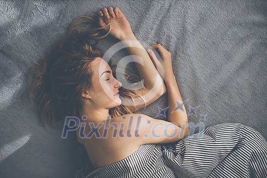 Pretty, young woman sleeping in her bed late in the morning on a weekend - compensating for the lack of sleep Pretty, young woman sleeping in her bed late in the morning on a weekend - compensating for the lack of sleep